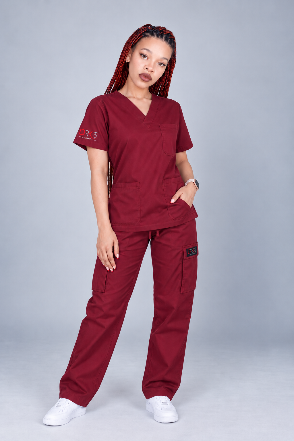 DRKT model wearing burgundy scrubs with a V-neck top, chest pocket and straight-leg bottoms